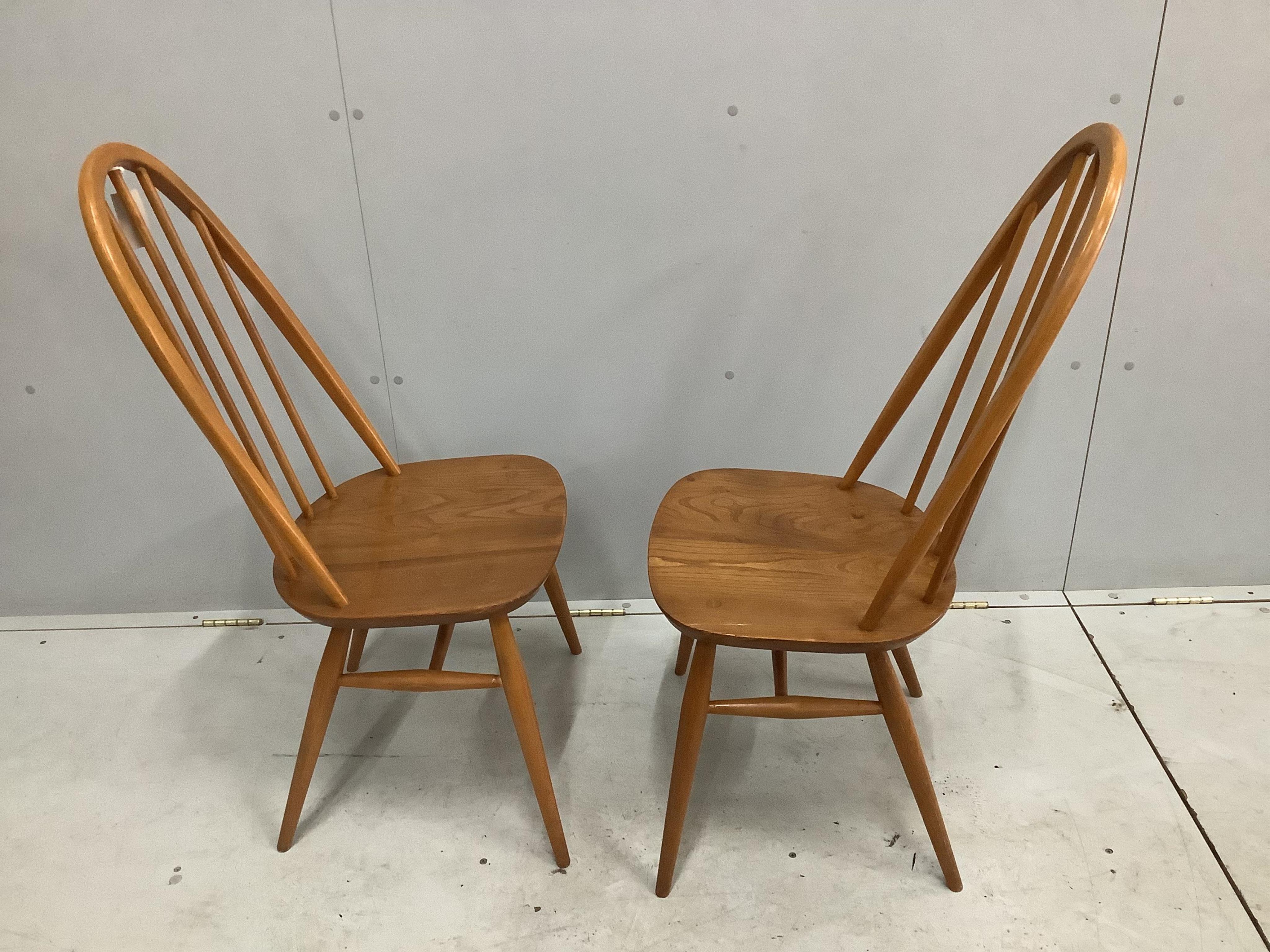 A pair of mid century Ercol elm and beech comb back dining chairs, height 96cm. Condition - fair to good, one with some damage to the top rail